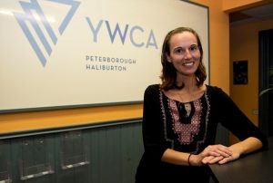 Carissa McIntyre, smiling in front of the YWCA logo