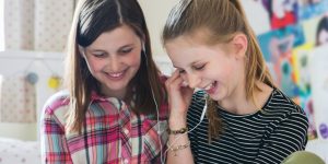 two teenage girls laughing and listening to music