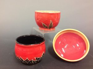 three red and black ceramic bowls arranged in a display