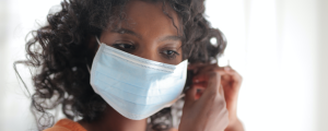 a young woman carefully tightens her medical mask over her face