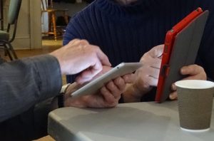 two pairs of seniors' hands holding an iphone and tablet