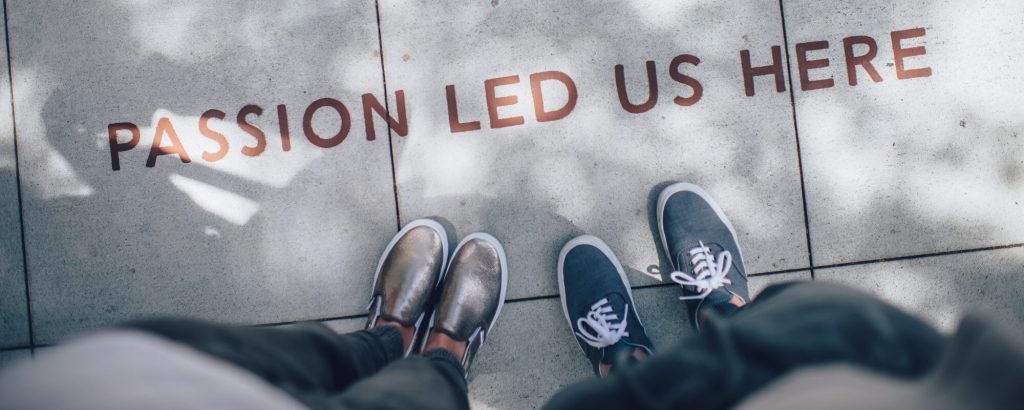 Image of two pairs of feet standing on the sidewalk beneath the words "passion led us here"