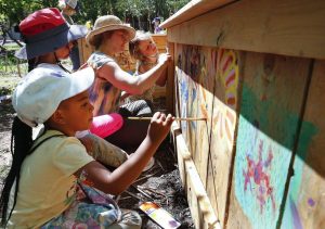Children paint colourful images on a wooden planter at Rowan Tree Children's School